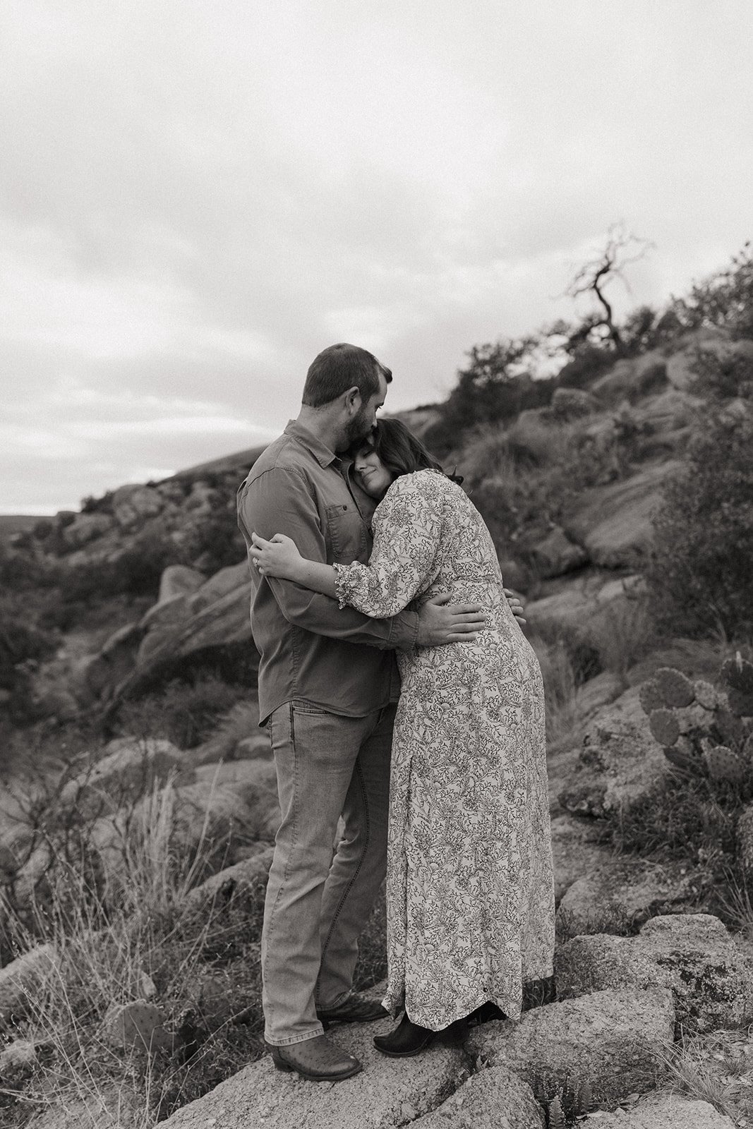 Black and white photo of the couple holding each other with Joshua Tree kind of vibes
