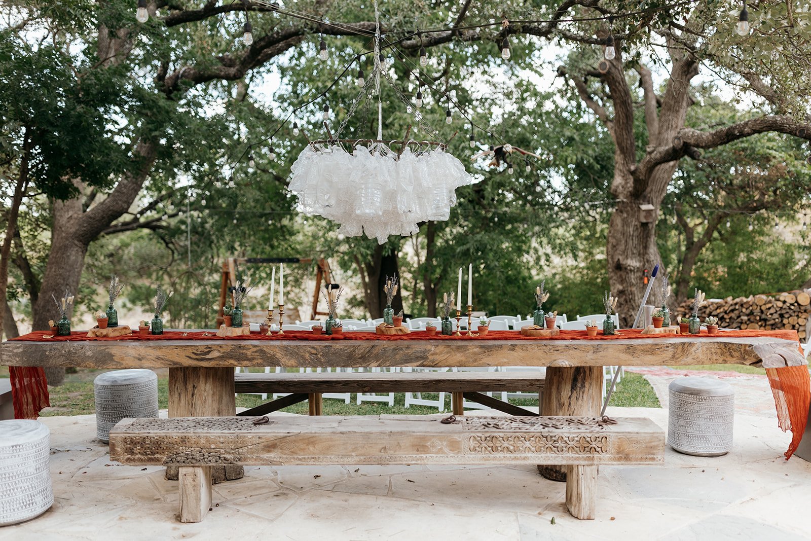 A beautiful chandelier hangs from the trees above the intimate wedding table setting