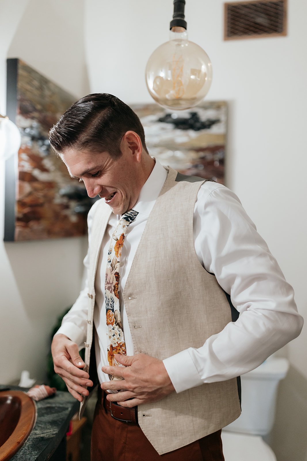 Portrait shot of James buttoning up his groom's vest