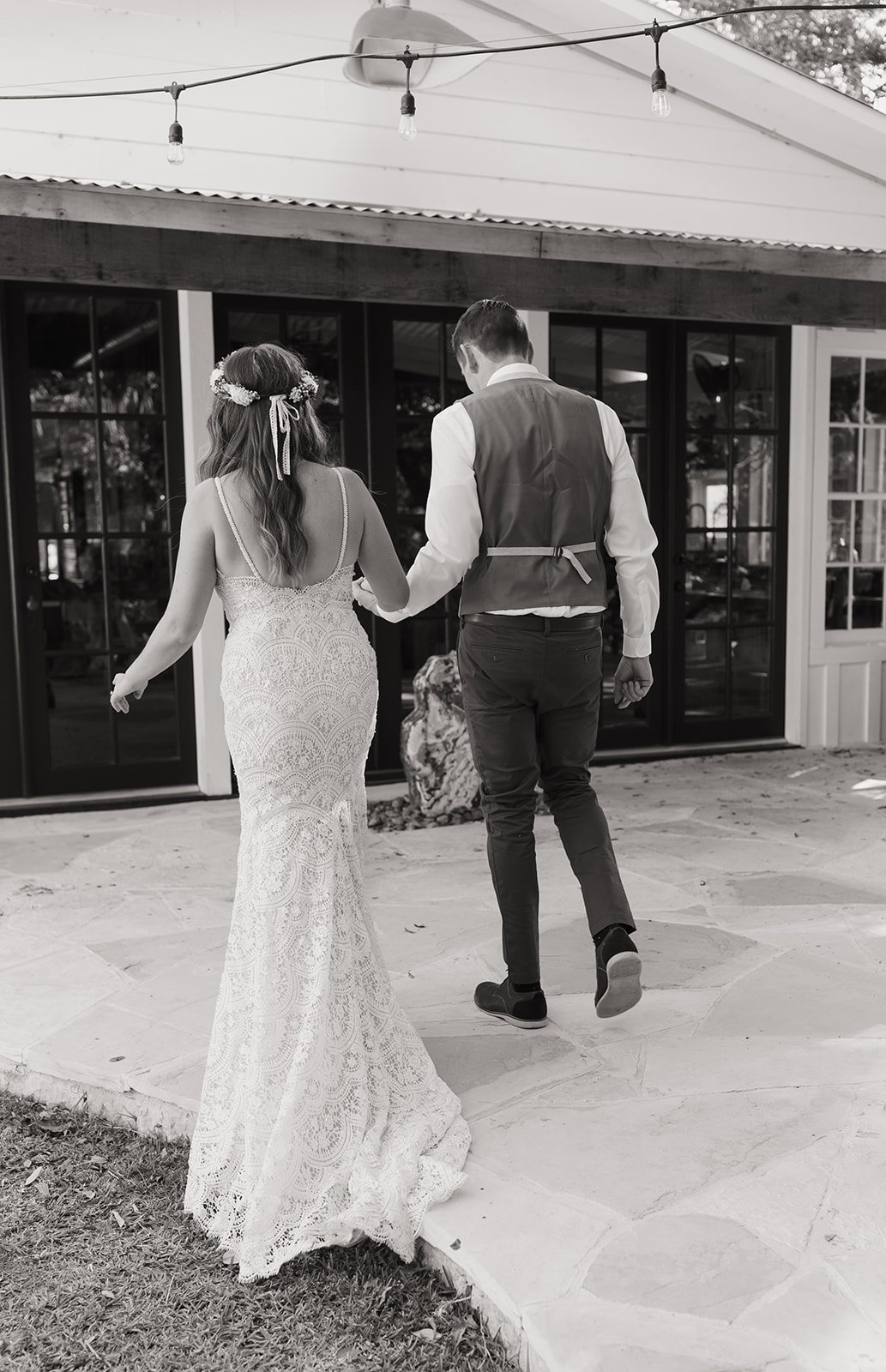 Black and white photo of Leah and James holding hands heading towards the Main Lodge