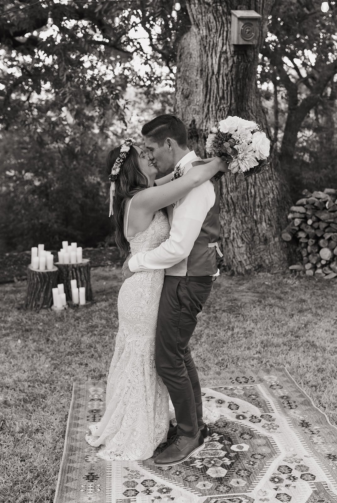 Black and white portrait of the couple kissing near the ceremony site