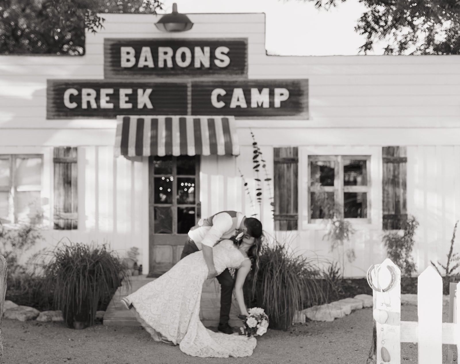 Black and white photo of Leah and James in front of Baron's Creek Camp lodge