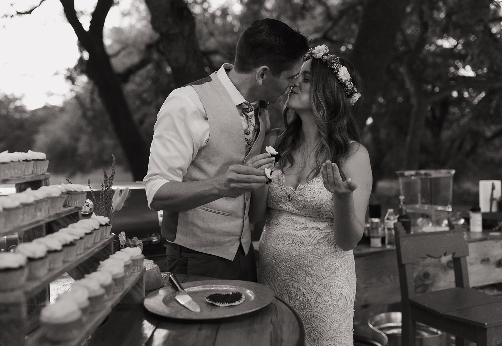 Black and white photo of couple kissing over cupcakes