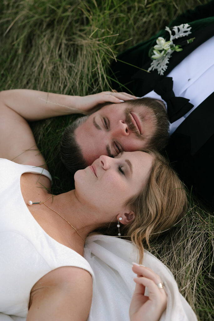 Wedding couple laying in the grass of a mountain meadow in Jackson Hole, Wyoming