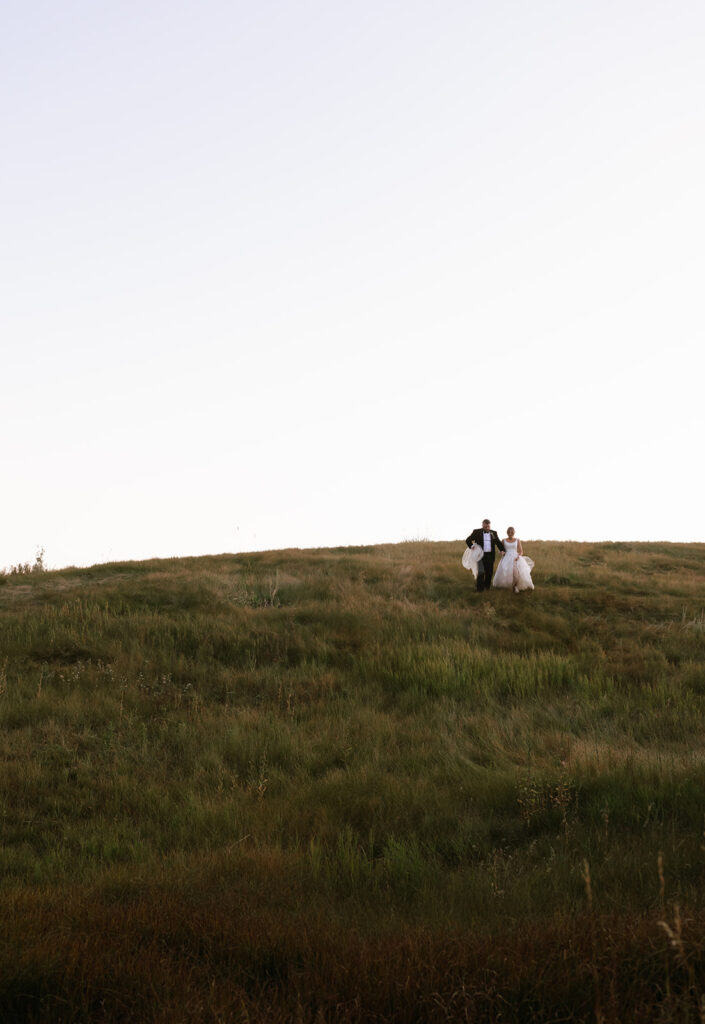 Wedding couple running down a mountain meadow for cinematic wedding portraits during the Jackson Hole wedding at Spring Creek Ranch