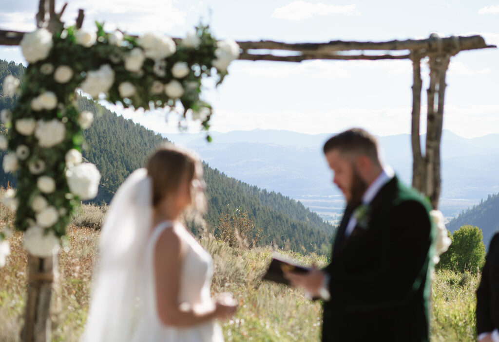 The couple reading their vows framed by stunning panoramic mountain views at Spring Creek Ranch wedding venue
