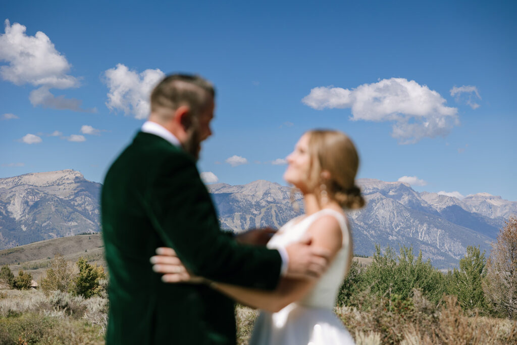 Spring Creek Ranch wedding first look with the Teton Mountain Range in the background and couple blurred artfully in foreground