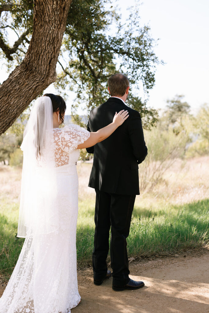 Sweet first look moment under the shade trees at Contigo Ranch before their wedding ceremony