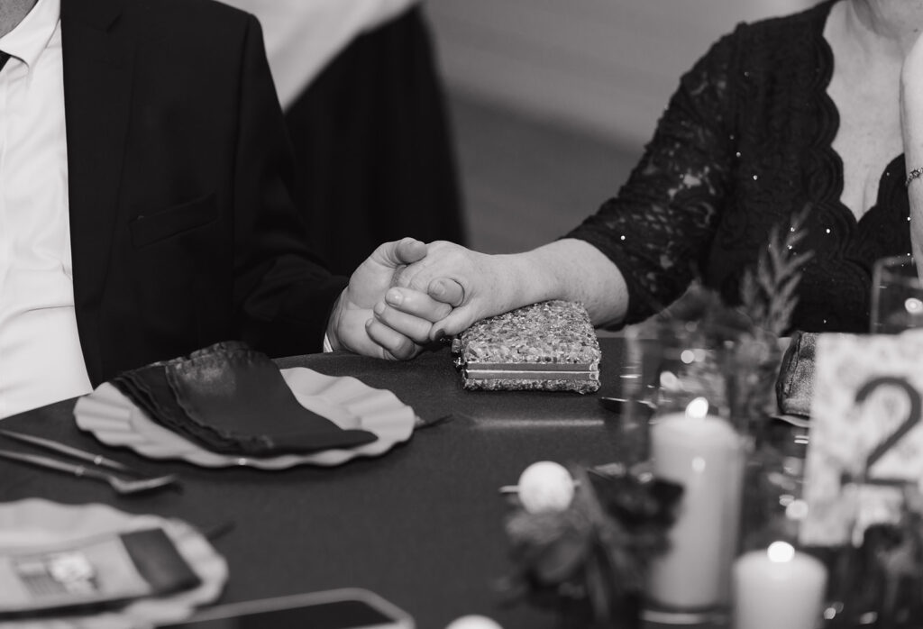 Couple holding hands during the wedding reception toasts