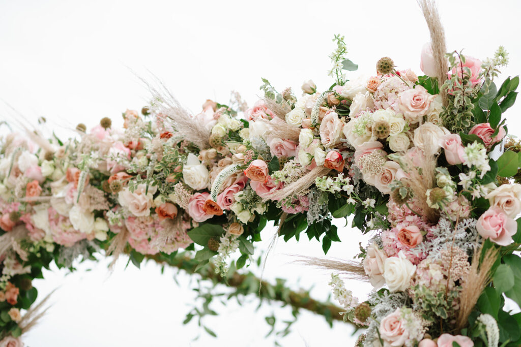 Sprays of pink and white flowers and verdant vines sprawling over their ceremony chuppah