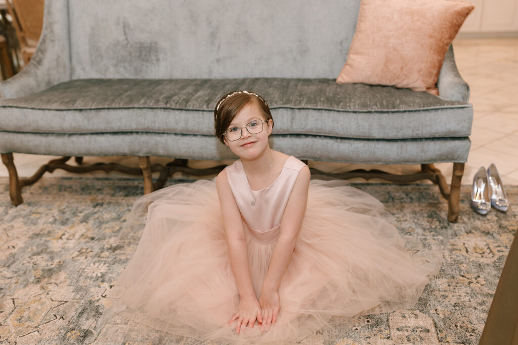 The flower girl sitting on the plush rug in The Videre Estate's luxurious and spacious getting ready suite