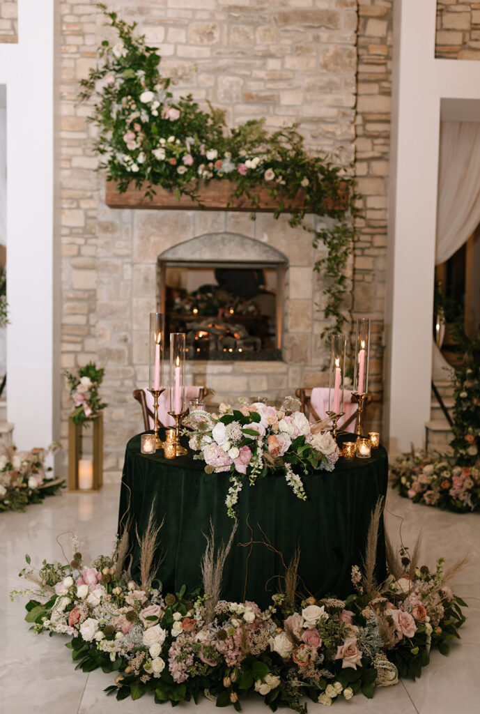 Romantic winter wedding sweethearts table with cascading florals and the Videre Estate fireplace behind them