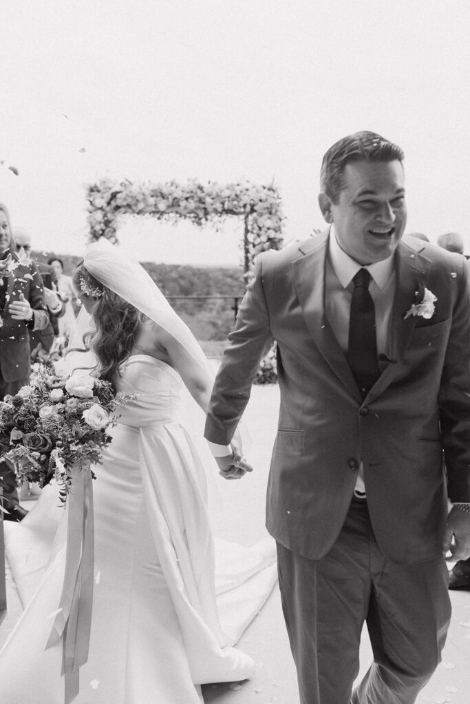 Sweet black and white in between moments of their recessional showered with flower petals