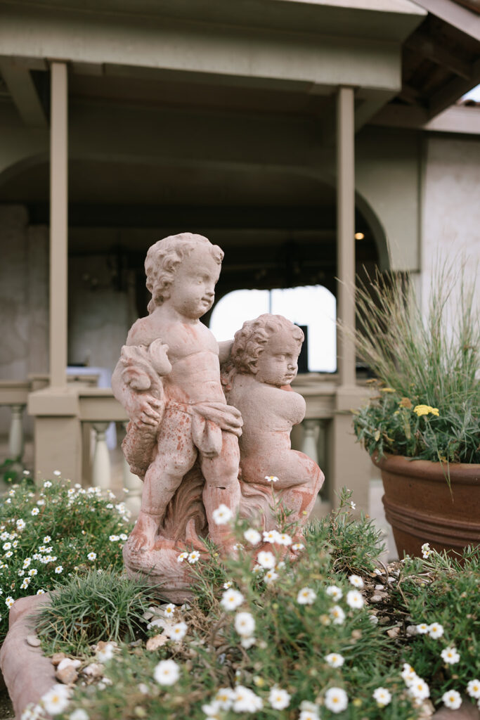 Gorgeous Tuscan wedding details with a cherub-style statue surrounded by flowers at Villa Antonia