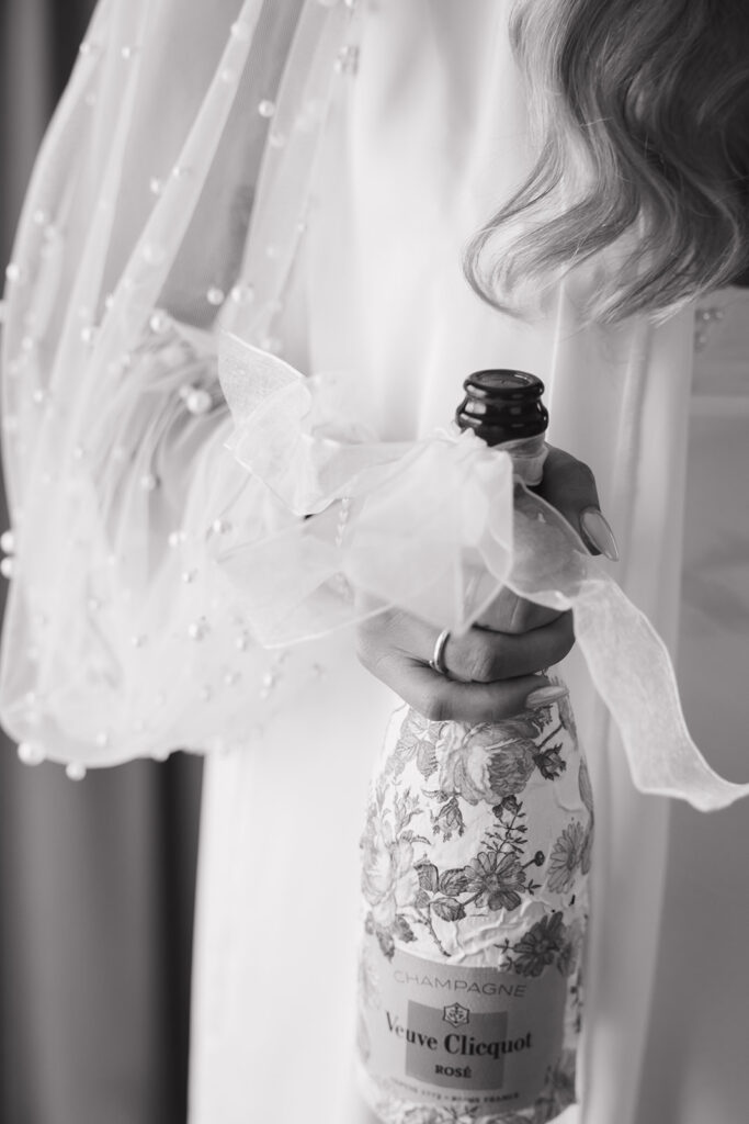 Bride opening champagne bottle in hotel suite for Austin TX getting ready photos at JW Marriott.