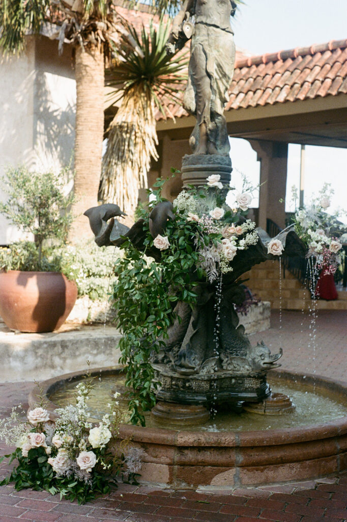 Floral arrangements and fountain in Villa Antonia courtyard, Tuscan-inspired wedding decor on 35mm film