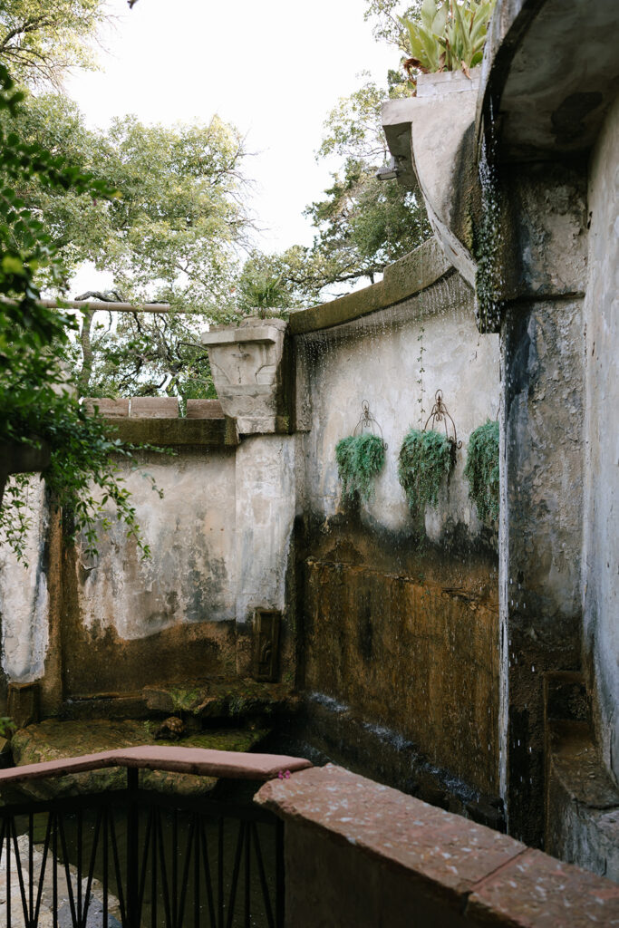 Stone wall water fountain pathway and lush plants Villa Antonia wedding reception