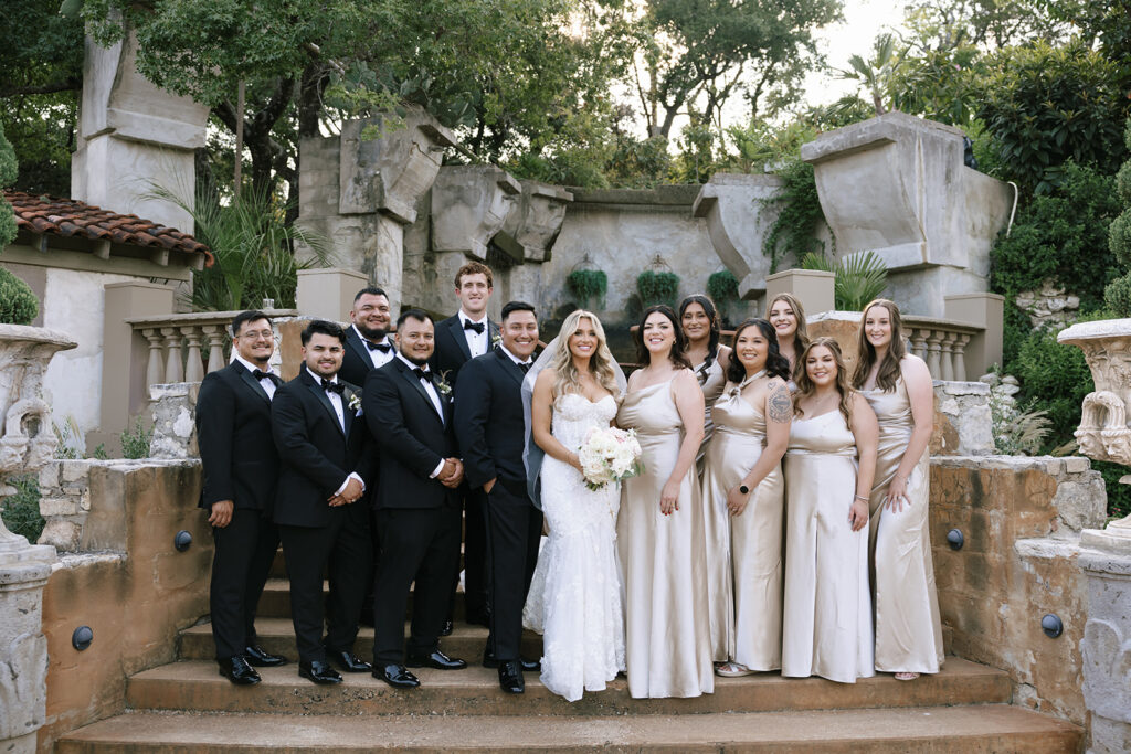 Bride and groom with bridal party in Villa Antonia courtyard, elegant wedding portrait