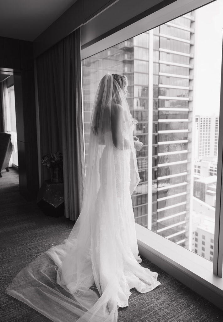 Bride in wedding veil looking out at Austin skyline for Austin TX wedding photos at JW Marriott.