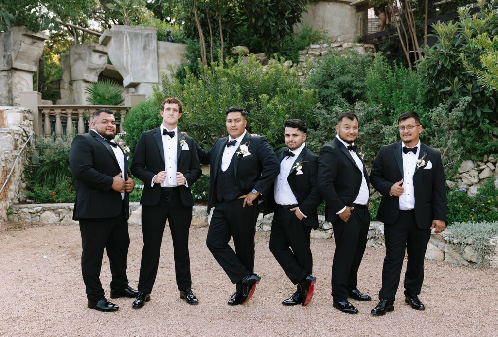 Groomsmen in tuxedos posing in Villa Antonia’s garden area