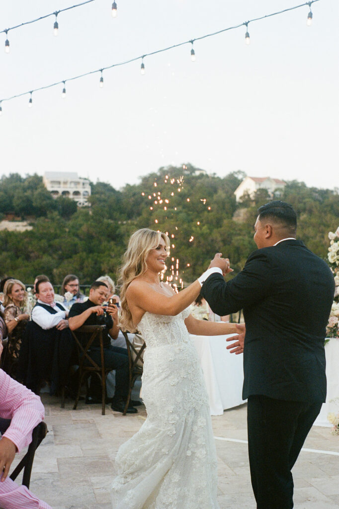 Bride and groom's first dance under string lights and sparklers with Austin hill country views in the background, shot on 35mm film