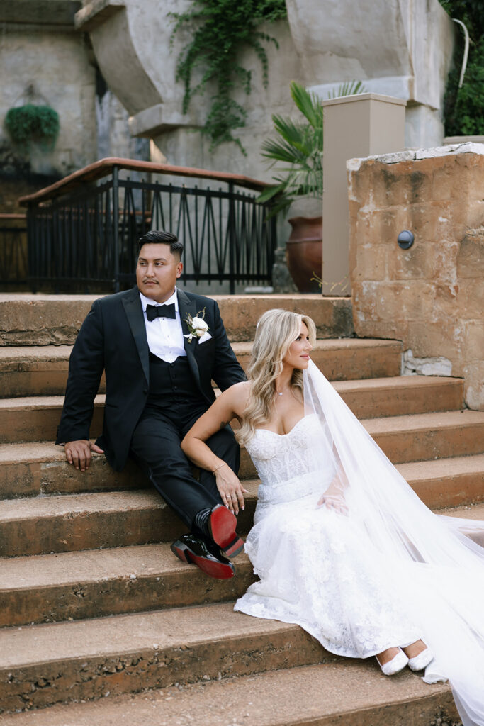 Bride and groom sitting close on the steps, enjoying a quiet moment together and a classy pose inspired by their engagement photos