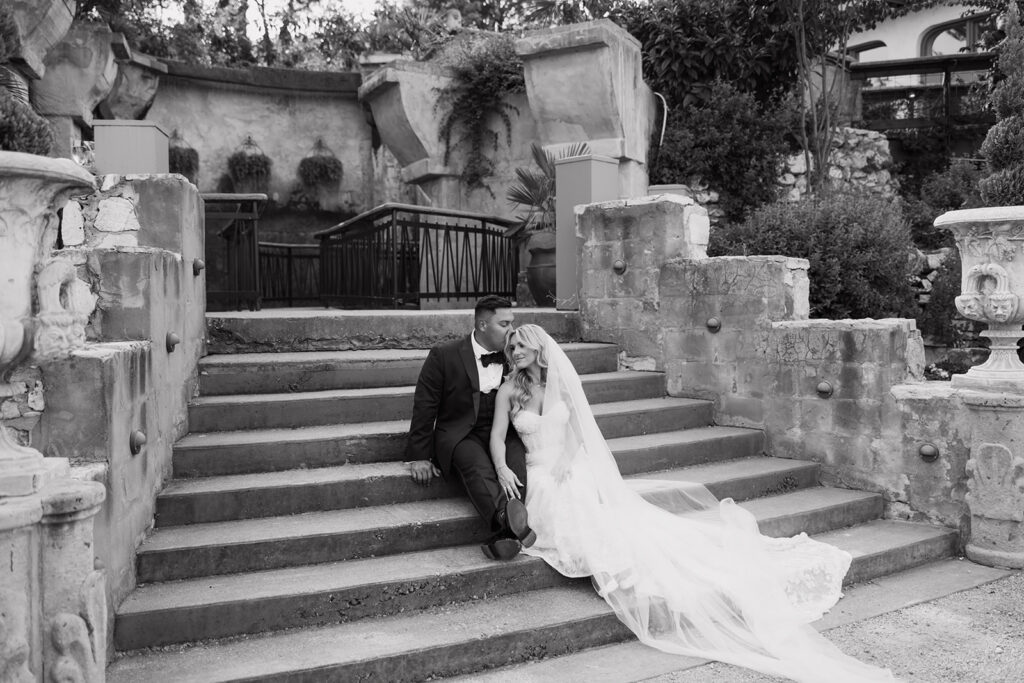 Bride and groom cozied up together on the stone steps at their Villa Antonia outdoor, European inspired wedding reception