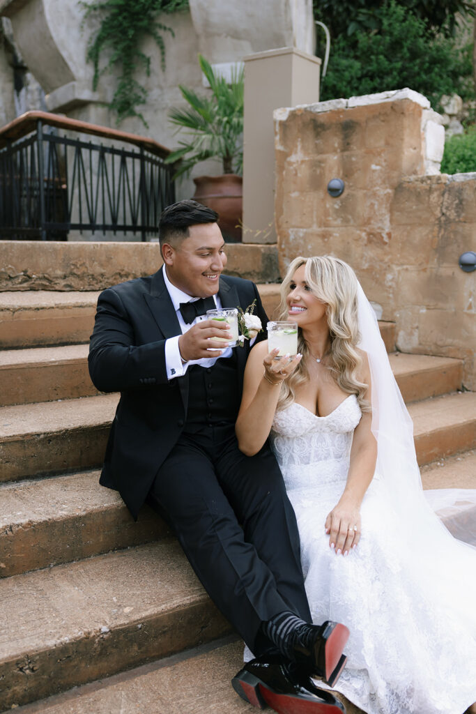 Bride and groom sharing a toast on stone steps at Villa Antonia wedding reception.