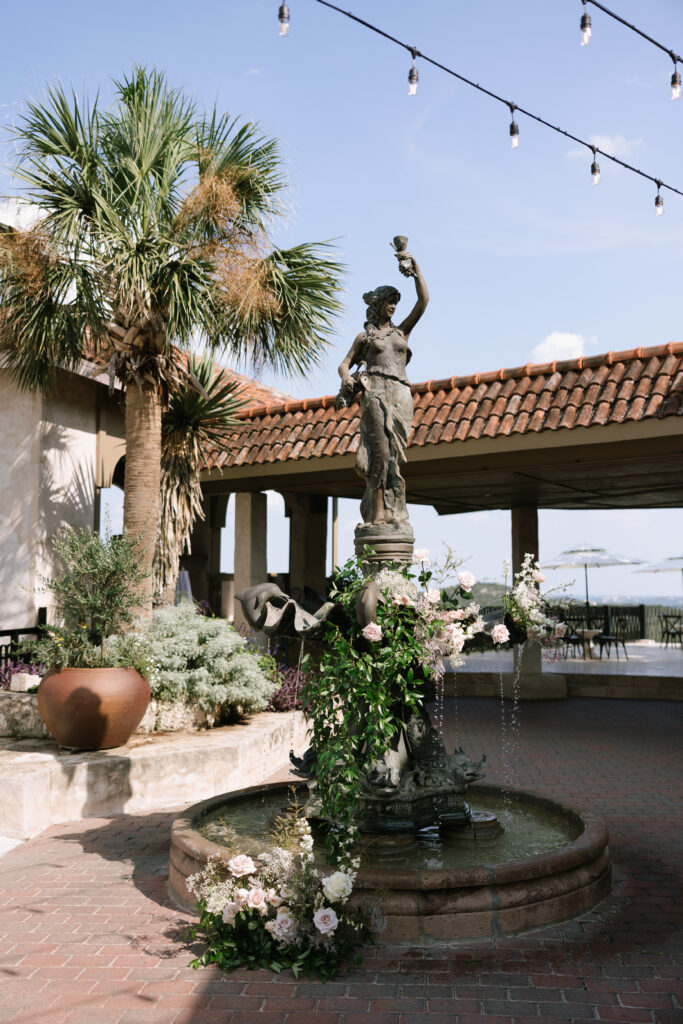 Statue with floral decor and string lights at Villa Antonia courtyard