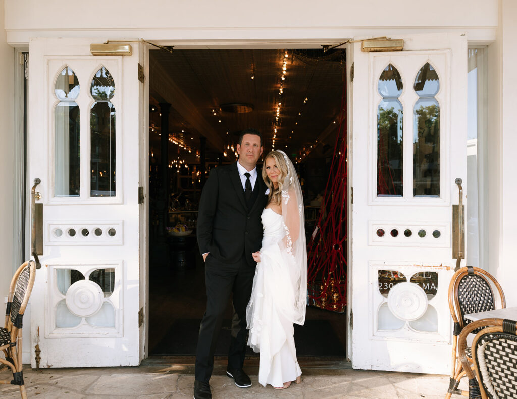 Bride and groom standing in front of historic white double doors in downtown Fredericksburg, moments after their Albert Hotel Fredericksburg wedding.