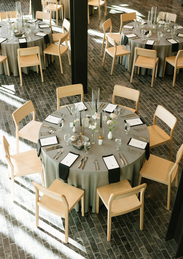 Overhead view of round reception tables with black napkins and natural wood chairs.