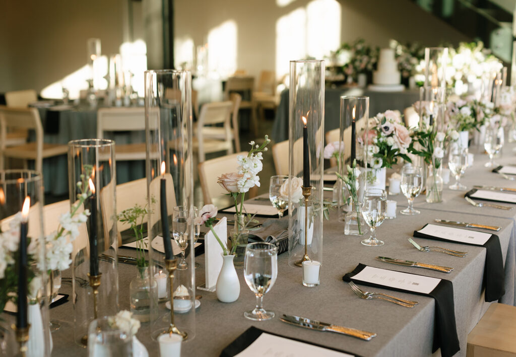 Modern and minimalist floral wedding centerpiece with glass candles and neutral tones.