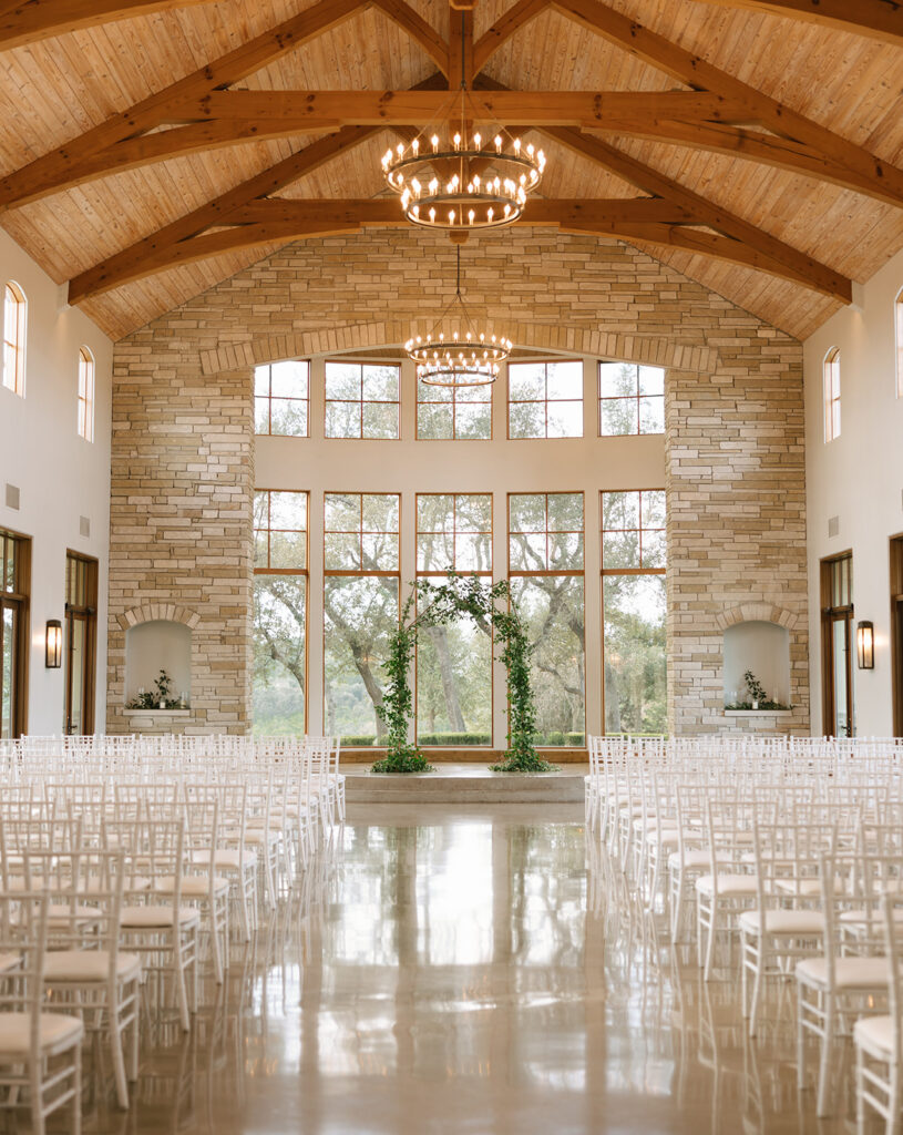 The gorgeous vaulted ceiling, stonework, floor to ceiling windows and metal chandeliers at Canyonwood Ridge in Dripping Springs Texas