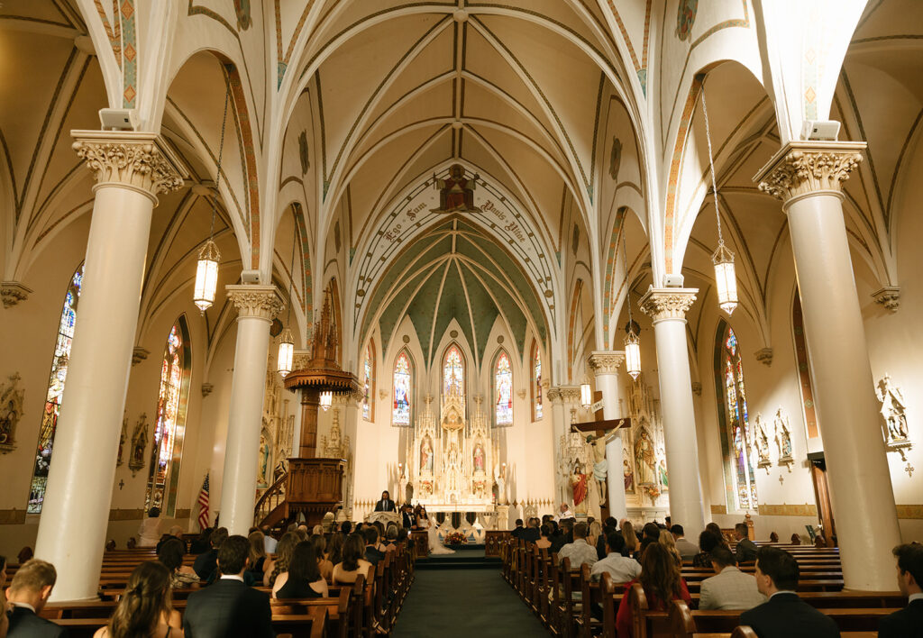 Full view of Shannon and Austin’s wedding ceremony from the back of St. Mary’s Catholic Church, with the altar and vaulted ceilings in frame.