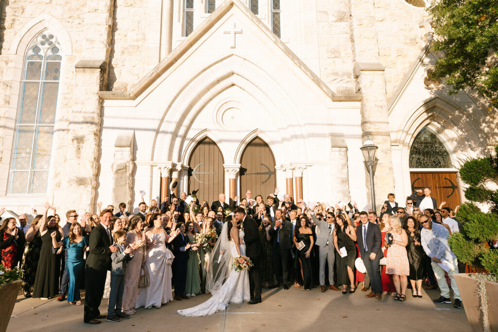 Full group photo of Shannon and Austin with all their guests in front of St. Mary’s Catholic Church in Fredericksburg, celebrating in the golden afternoon light.