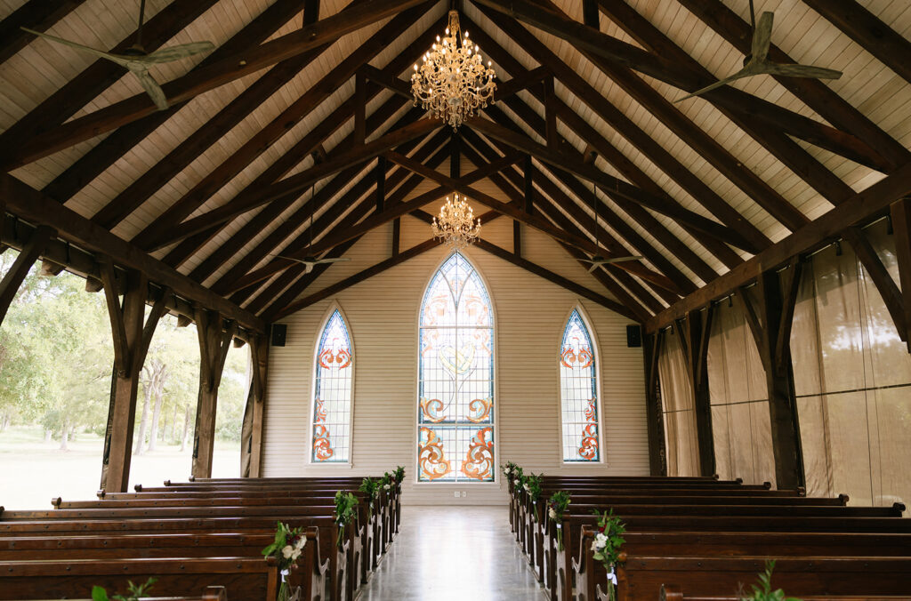 The open air outdoor chapel with gorgeous chandeliers, stain glass windows, and old wedding pews at La Bonne Vie Ranch in the heart of Fredericksburg Texas wine country