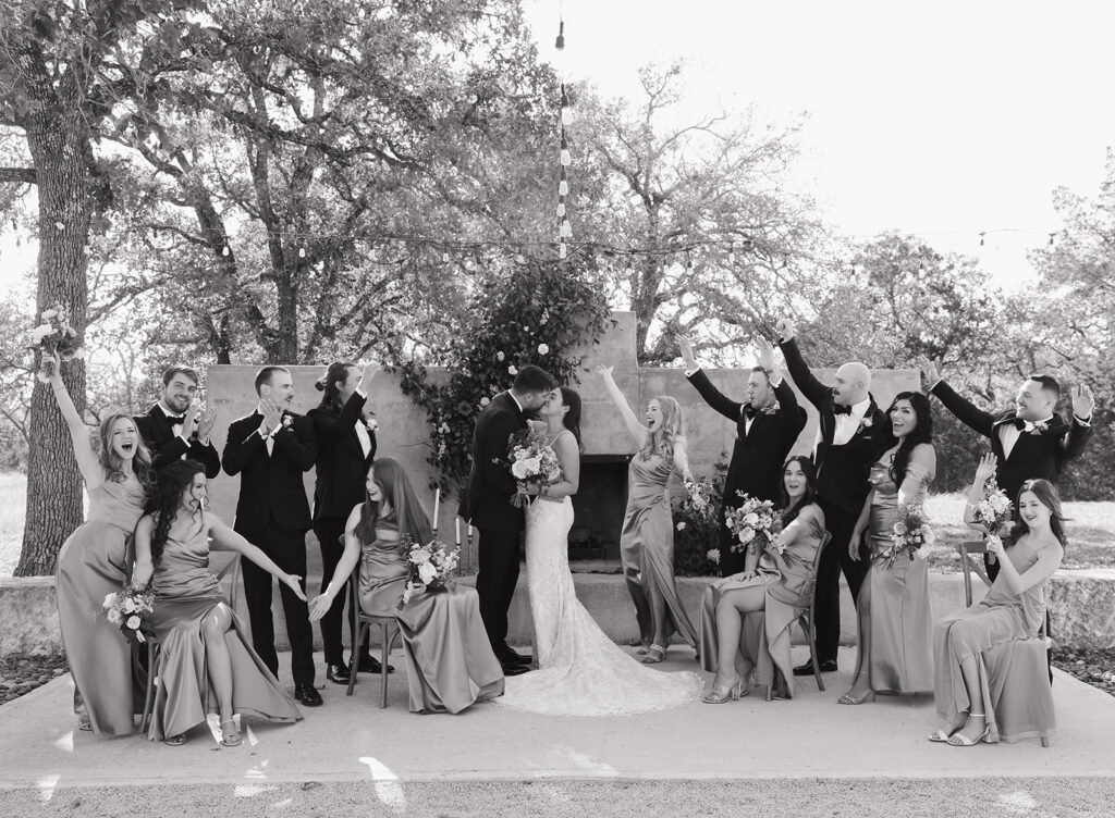 Black and white candid of the wedding party cheering for Shannon and Austin, captured during portraits at Swallows Eve’s southwest-inspired courtyard.