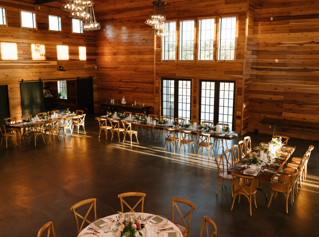 Reception table setup inside the barn at Swallows Eve, gold accents, candles, and elegant floral centerpieces for a candlelit dinner party atmosphere.