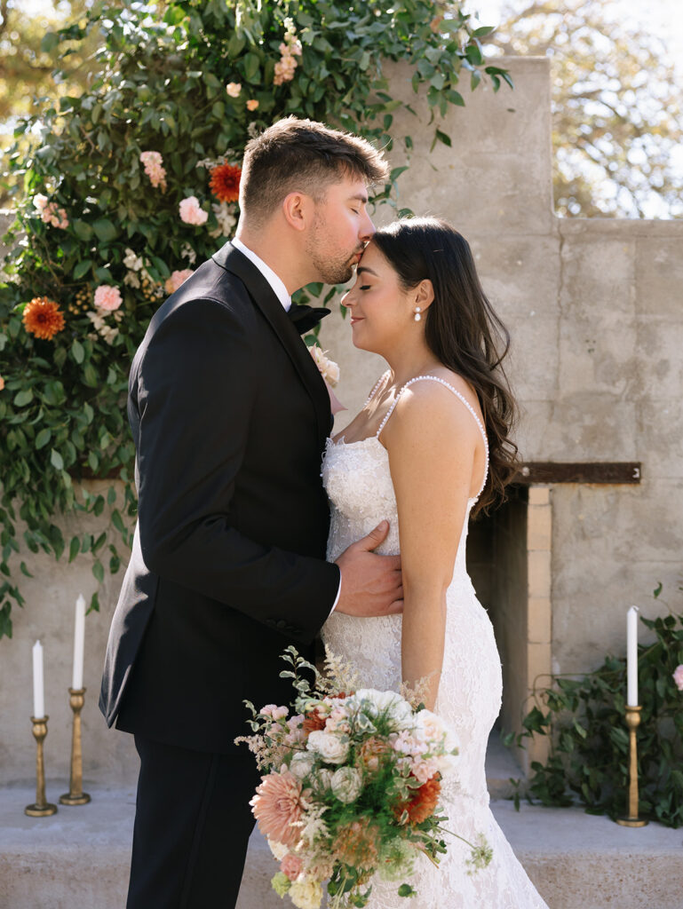 Shannon and Austin sharing their first look in the Fireside Courtyard at Swallows Eve, standing in front of the stone fireplace adorned with florals and taper candles.