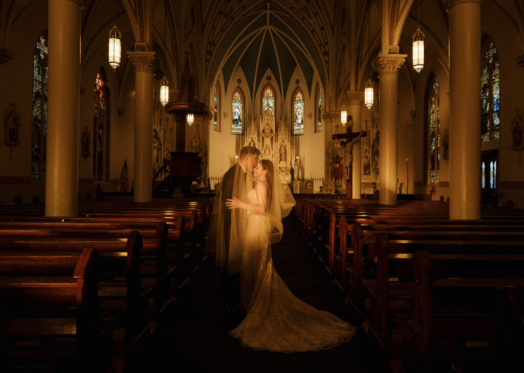 Shannon and Austin standing together in the center aisle of St. Mary’s in Fredericksburg Texas, embraced in the peaceful afterglow of their ceremony.