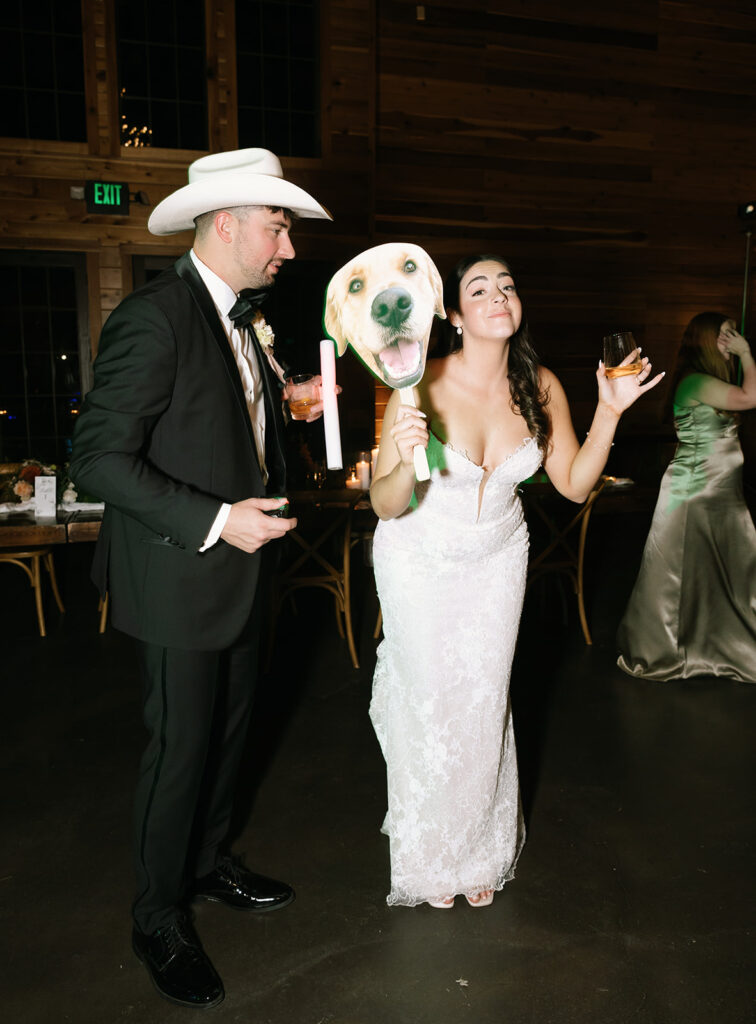 Austin and Shannon holding up a large face cutout of their dog during the dance party—one of the most fun and memorable moments from the night.