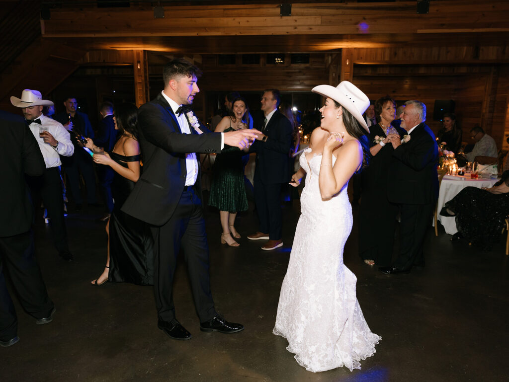 Austin twirling Shannon on the dance floor at Swallows Eve, her hat and gown catching the reception lights as guests cheer them on.