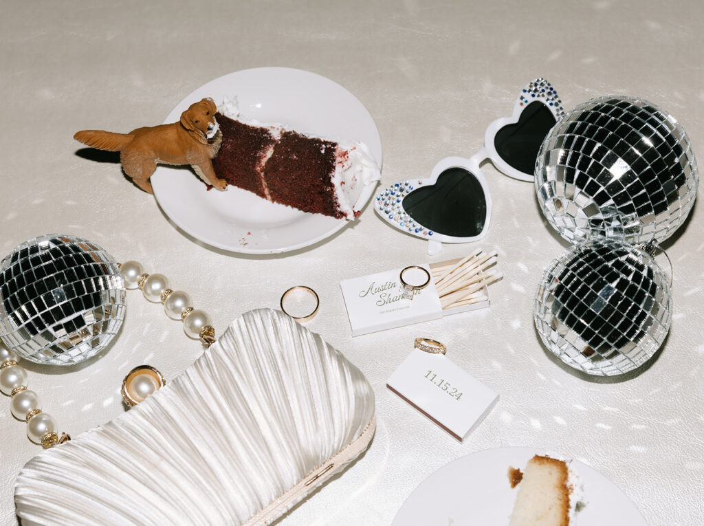 Creative flash flatlay of Swallows Eve wedding reception details, including mini disco balls, heart-shaped sunglasses, matchboxes, rings, and pearl accessories.