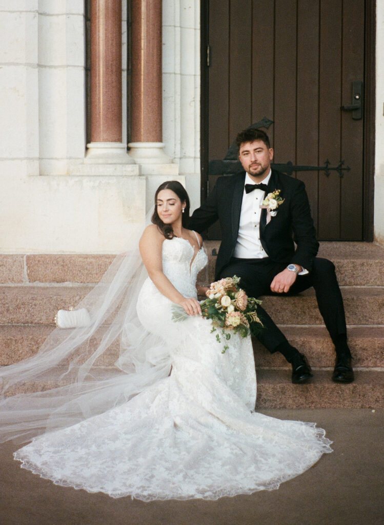 Timeless seated portrait of Shannon and Austin outside the church, captured on 35mm film with soft tones and natural light.