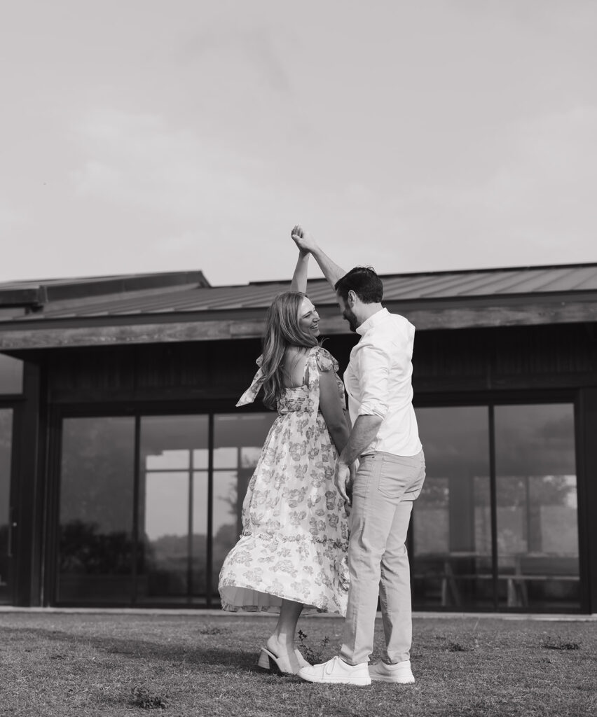 Black and white image of the couple dancing and laughing in front of the Walden Retreats venue during their engagement session.
