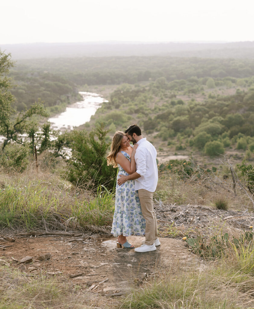 Couple embracing on a cliffside at Walden Retreats Johnson City, overlooking the Pedernales River and lush Hill Country views.