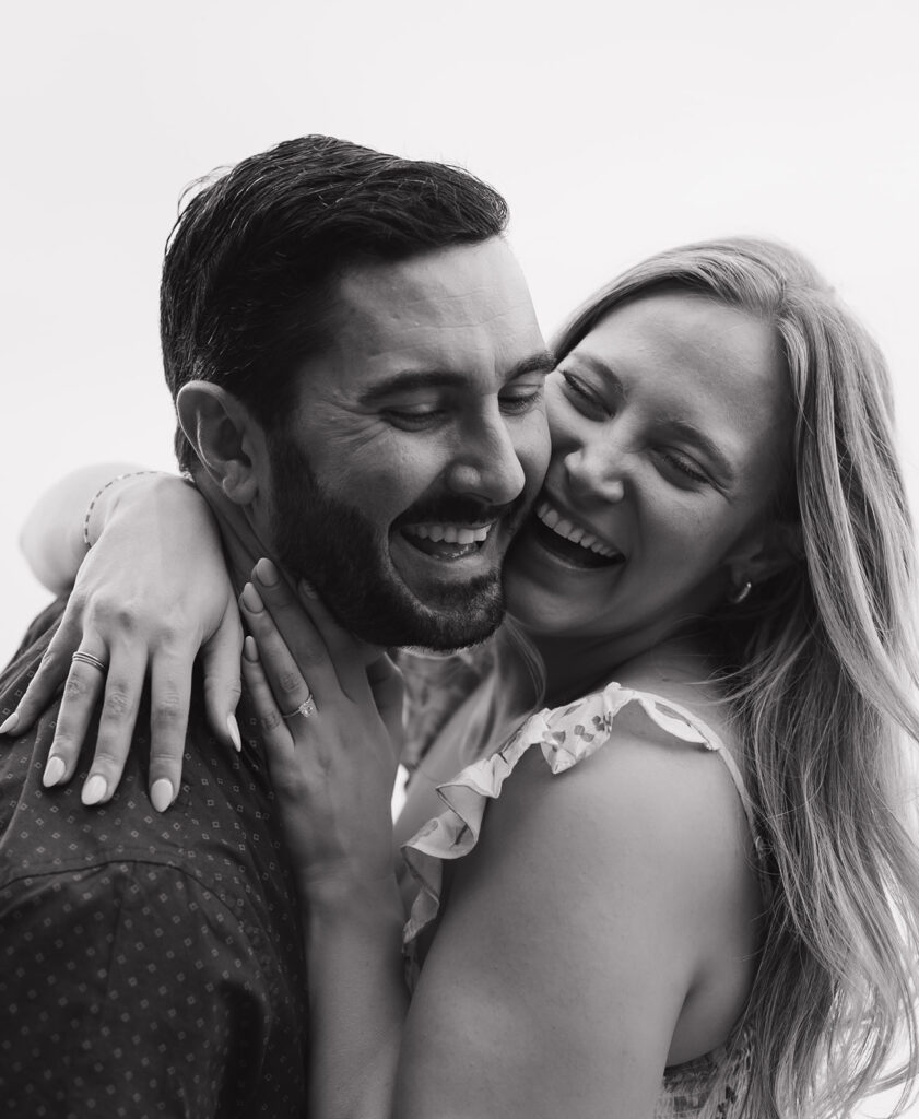 Candid close-up black and white photo of Sara and Kyle laughing and holding each other during their Walden Retreats engagement session.