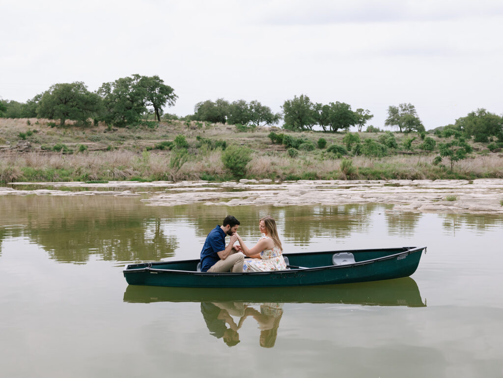 Sara and Kyle holding hands and smiling in the middle of the river, their canoe gently floating near the shore at Walden Retreats.